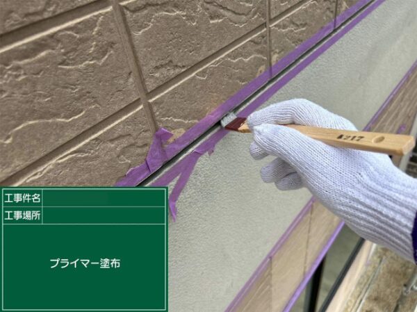 刷毛を使って外壁目地にプライマーを塗る手元の作業